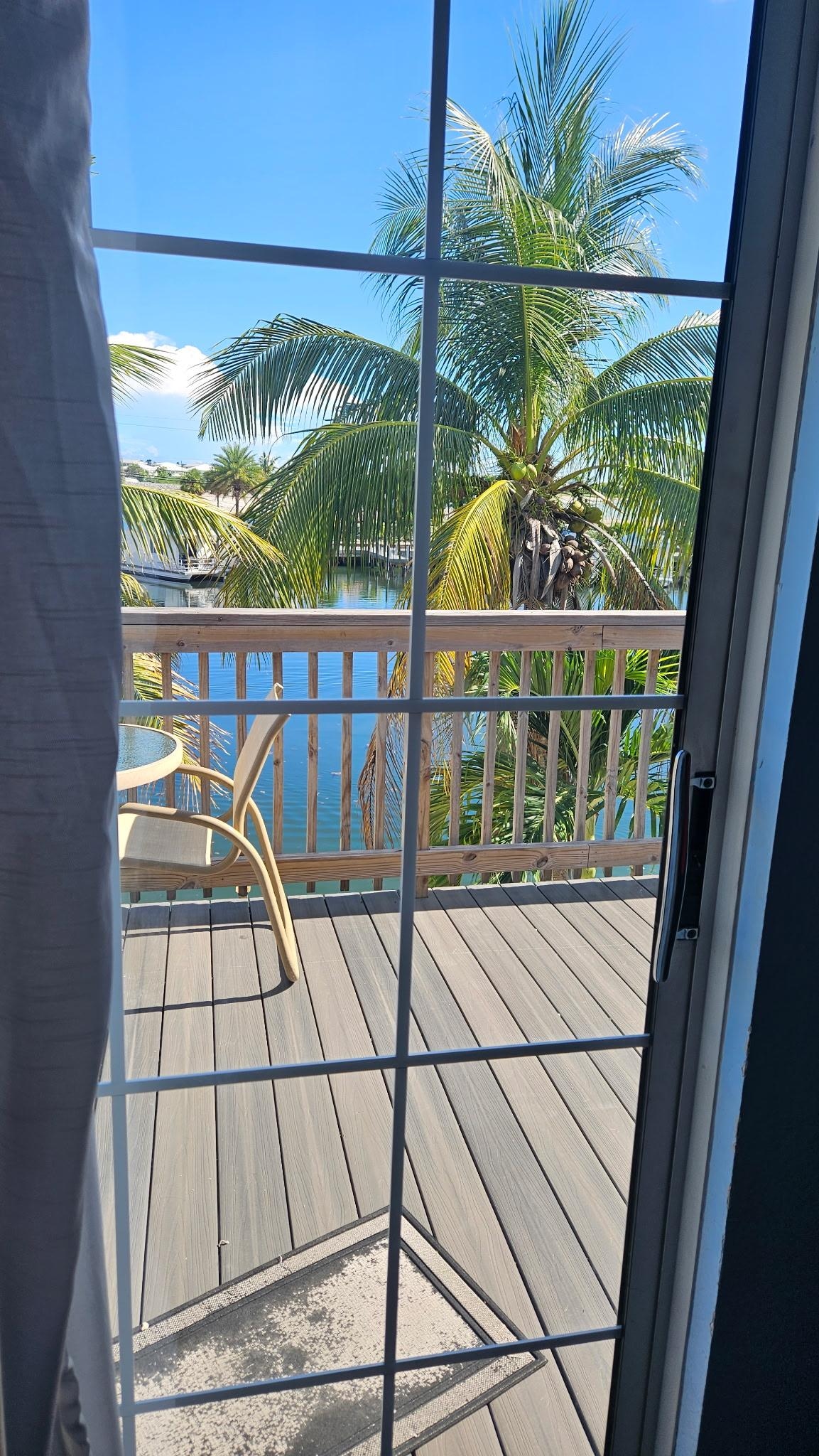 Sunny and pleasant view of the deck and water below through the sliding glass doors.