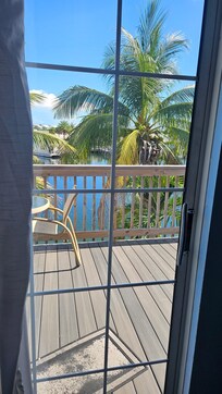 Sunny and pleasant view of the deck and water below through the sliding glass doors.