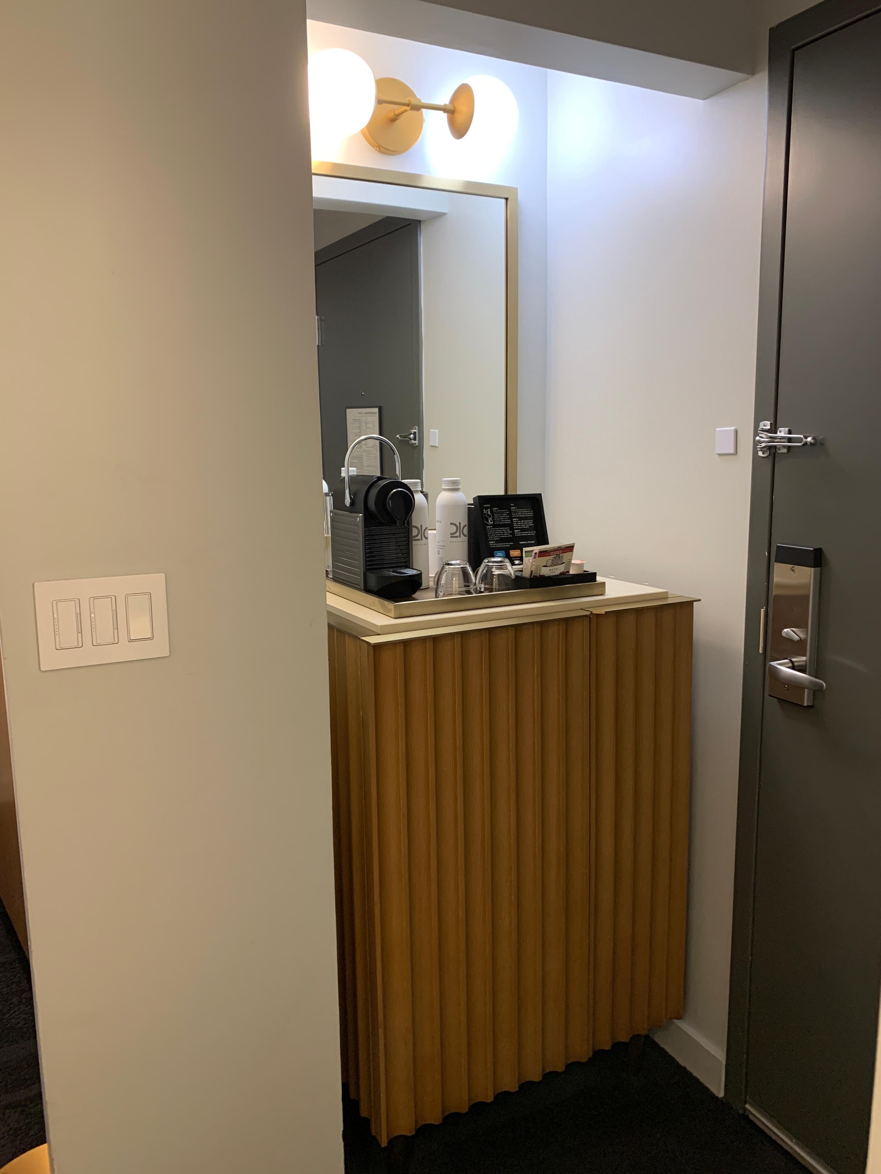 Entrance to guest room with Nespresso coffee machine and water bottles sitting on top of refrigerator