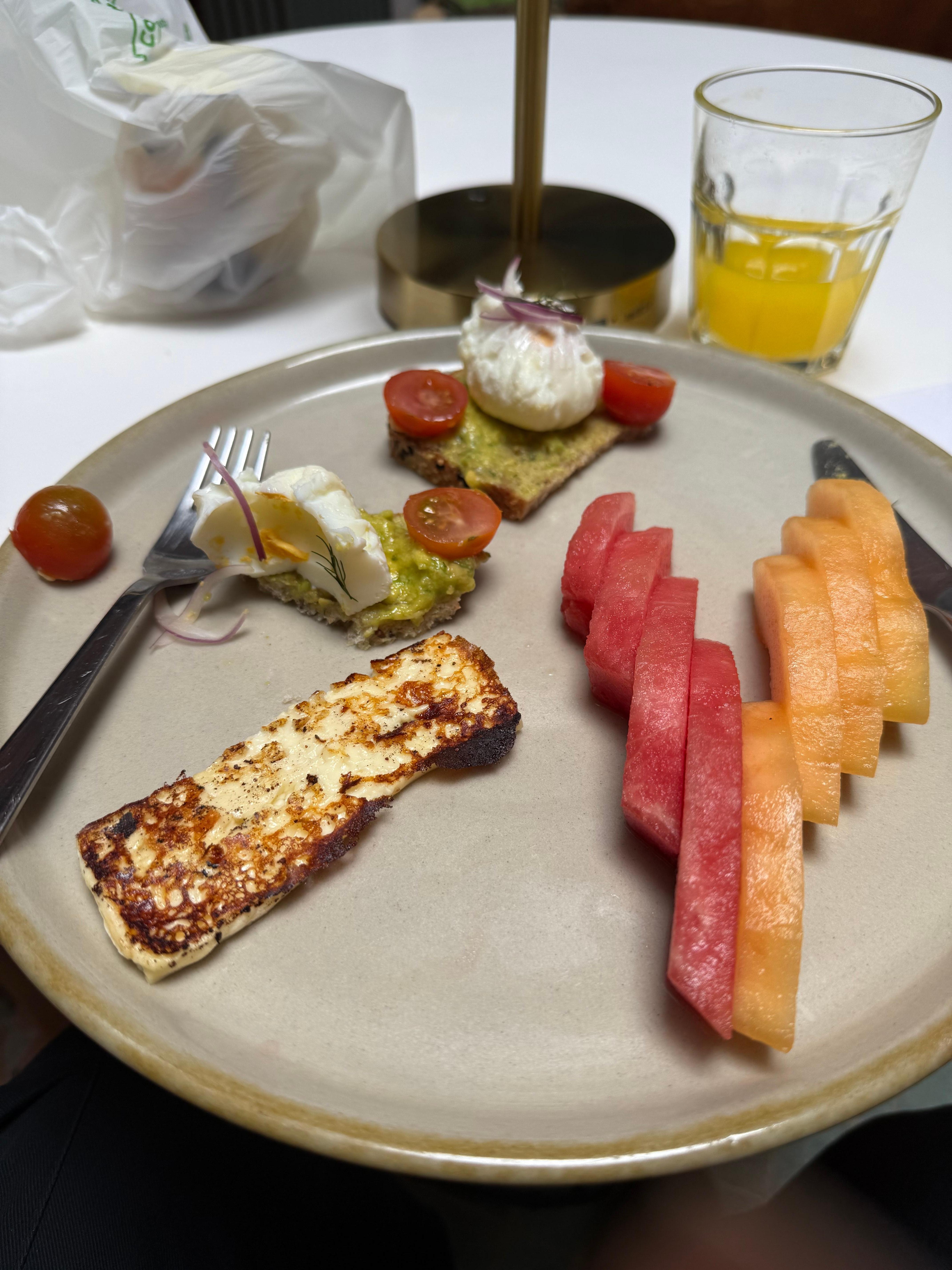 A breakfast; poached eggs, guacamole, melon…