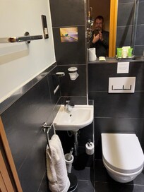 There is a walk-in, black tiled shower to the right. All very stylish and compact.
