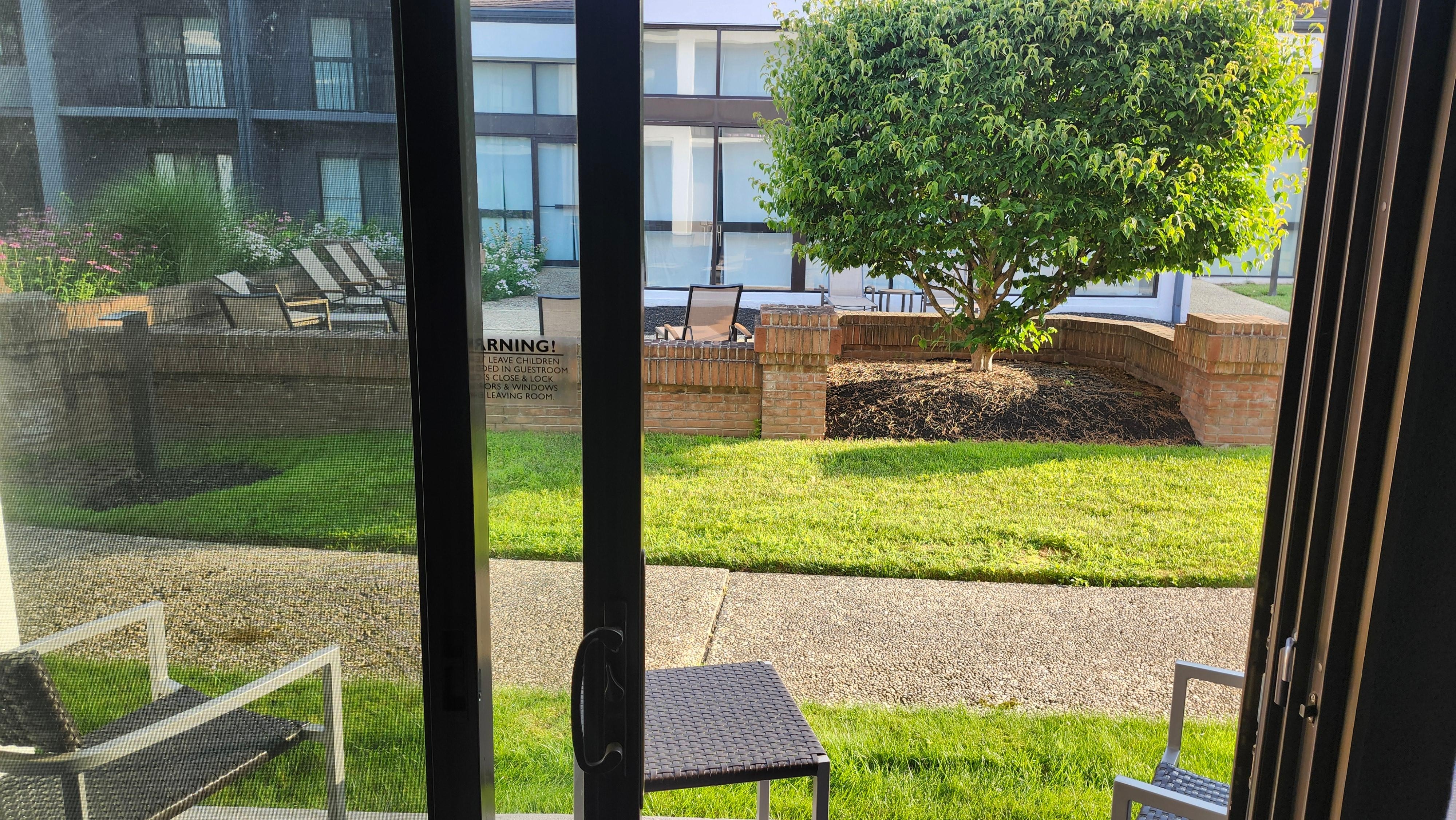 View from room of patio in foreground and enclosed courtyard beyond.