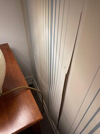 Main bedroom, wallpaper and only bedside cabinet covered in dust