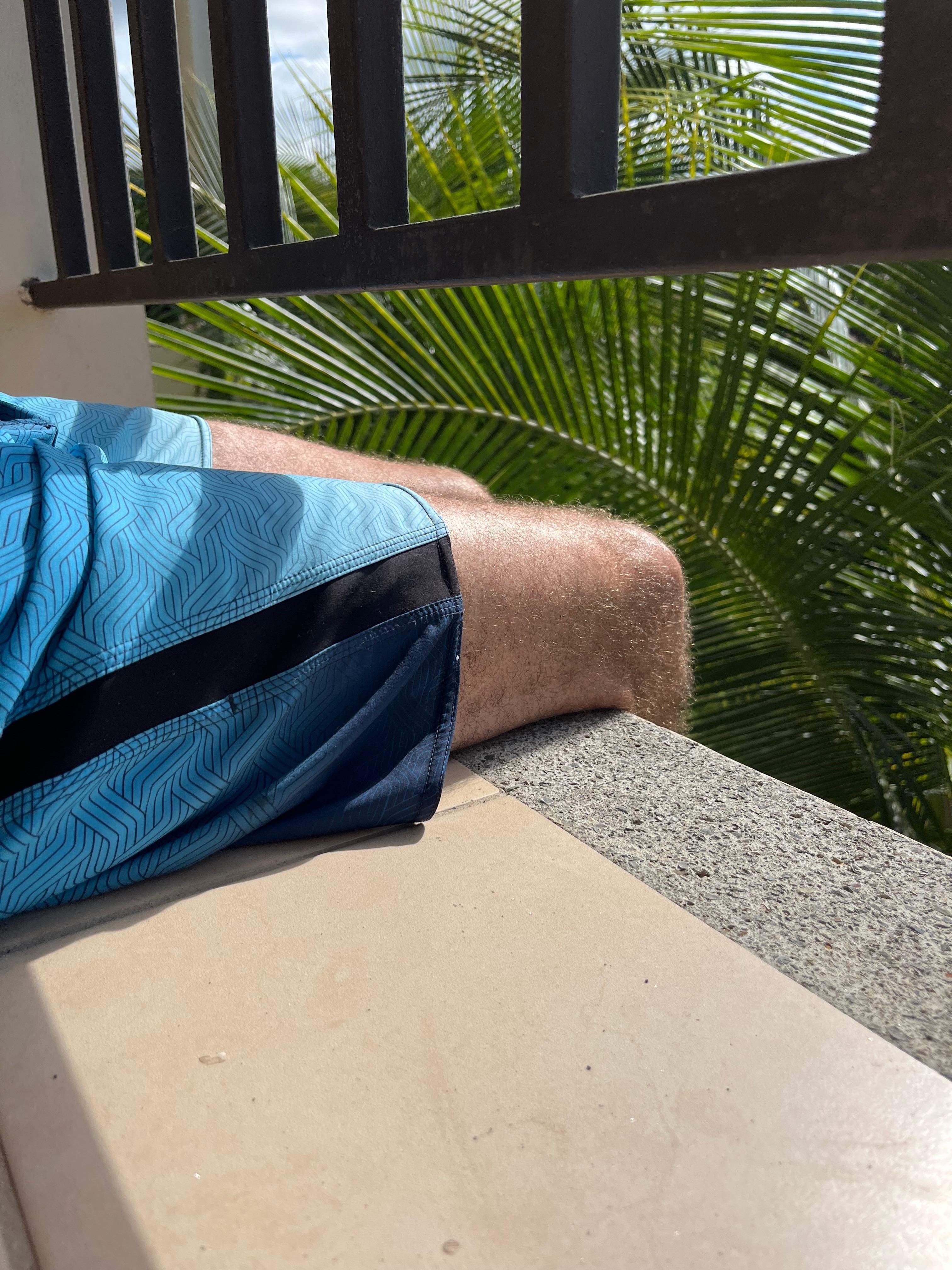 6 foot tall adult sitting under railing.  