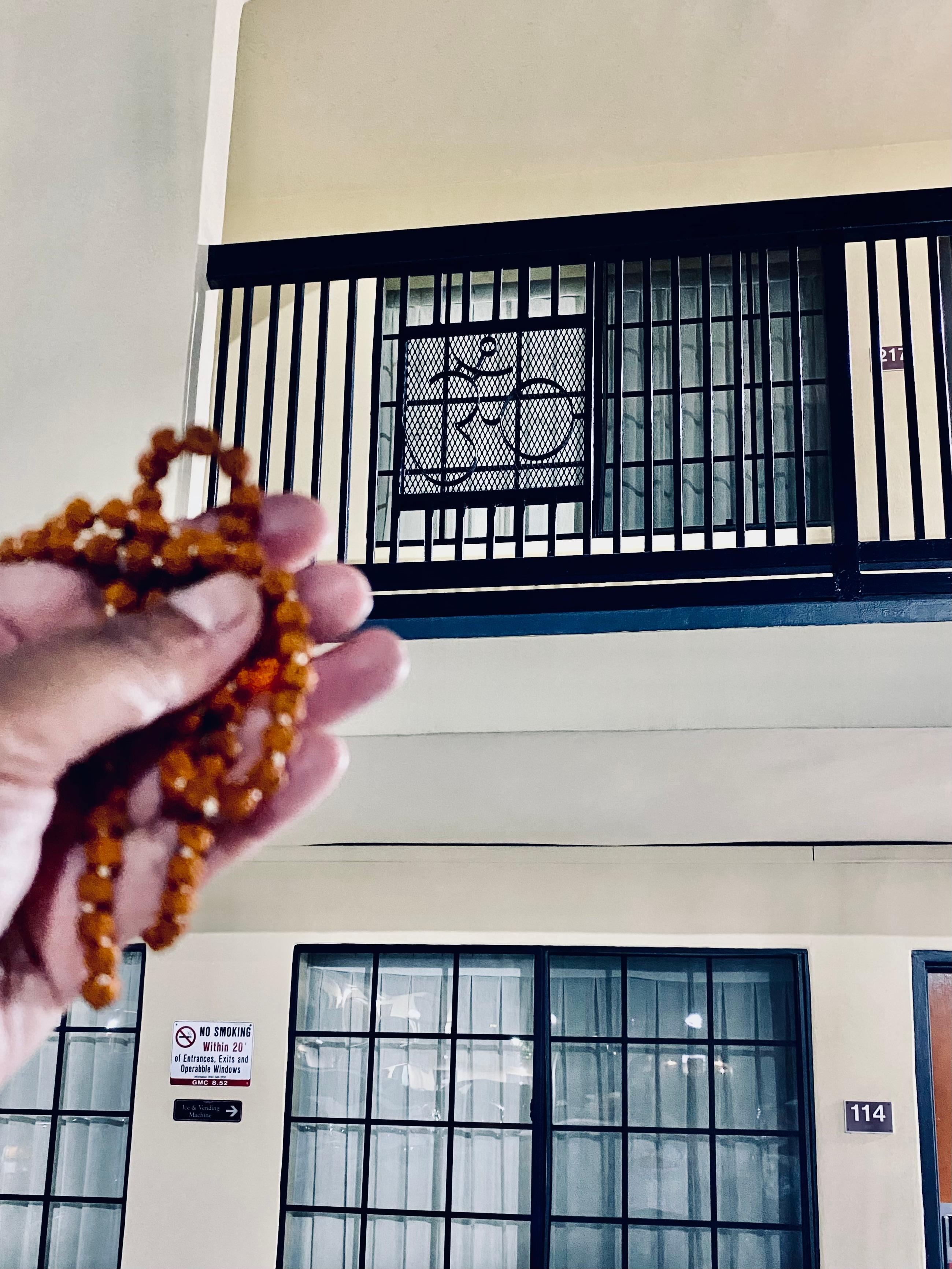 My Rudraksha mala that I use for meditating being held up to the Om railing.