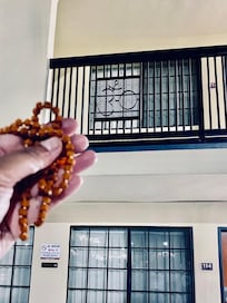 My Rudraksha mala that I use for meditating being held up to the Om railing.