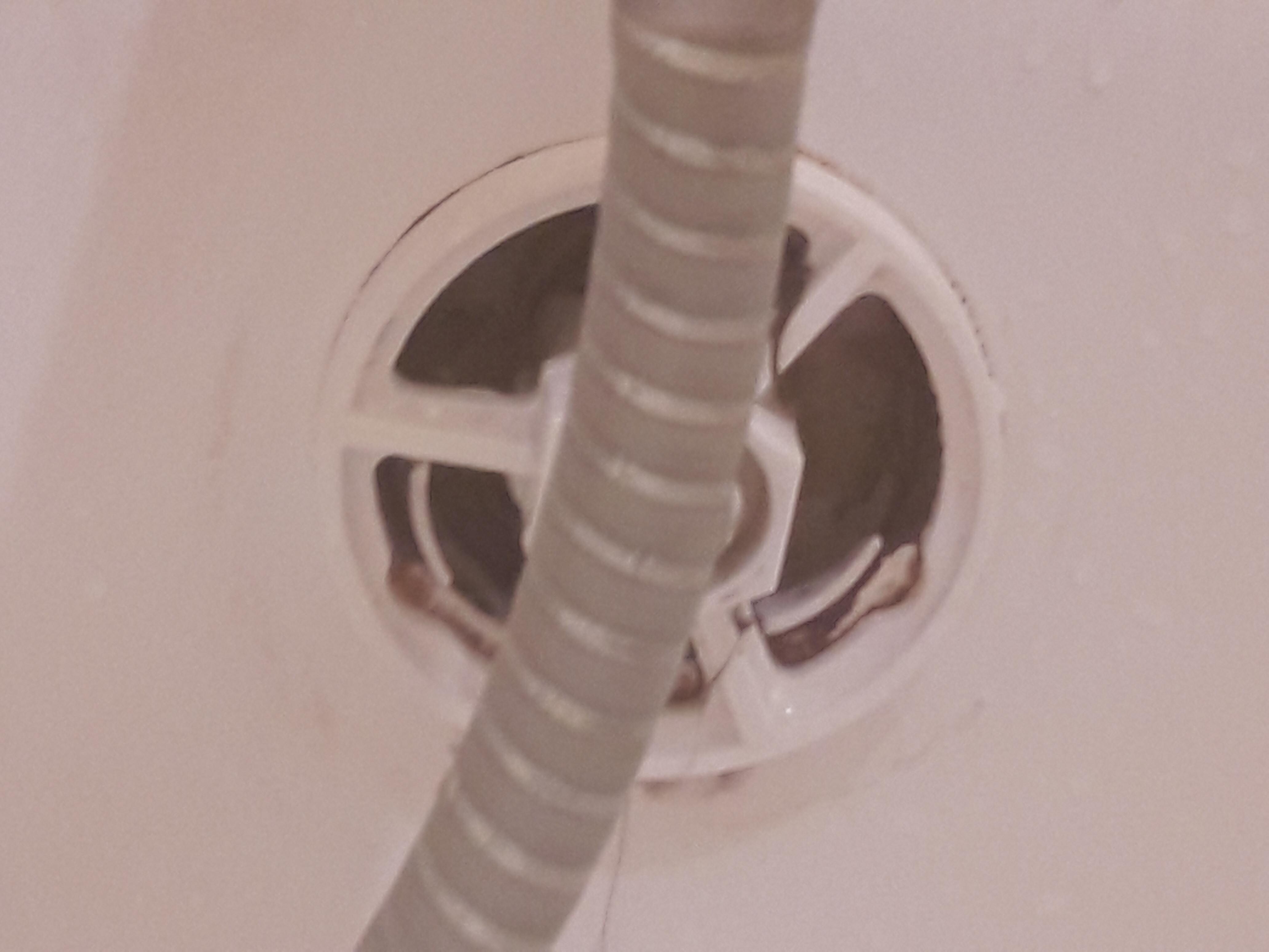 Bouchon d'évacuation de la baignoire très sale incrusté de cheveux et résidus.