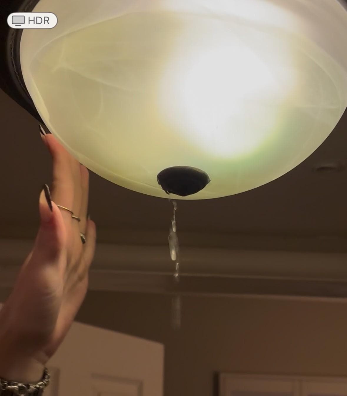 Water dripping from the light fixture.  The water level is clearly visible near the top of the glass cover.