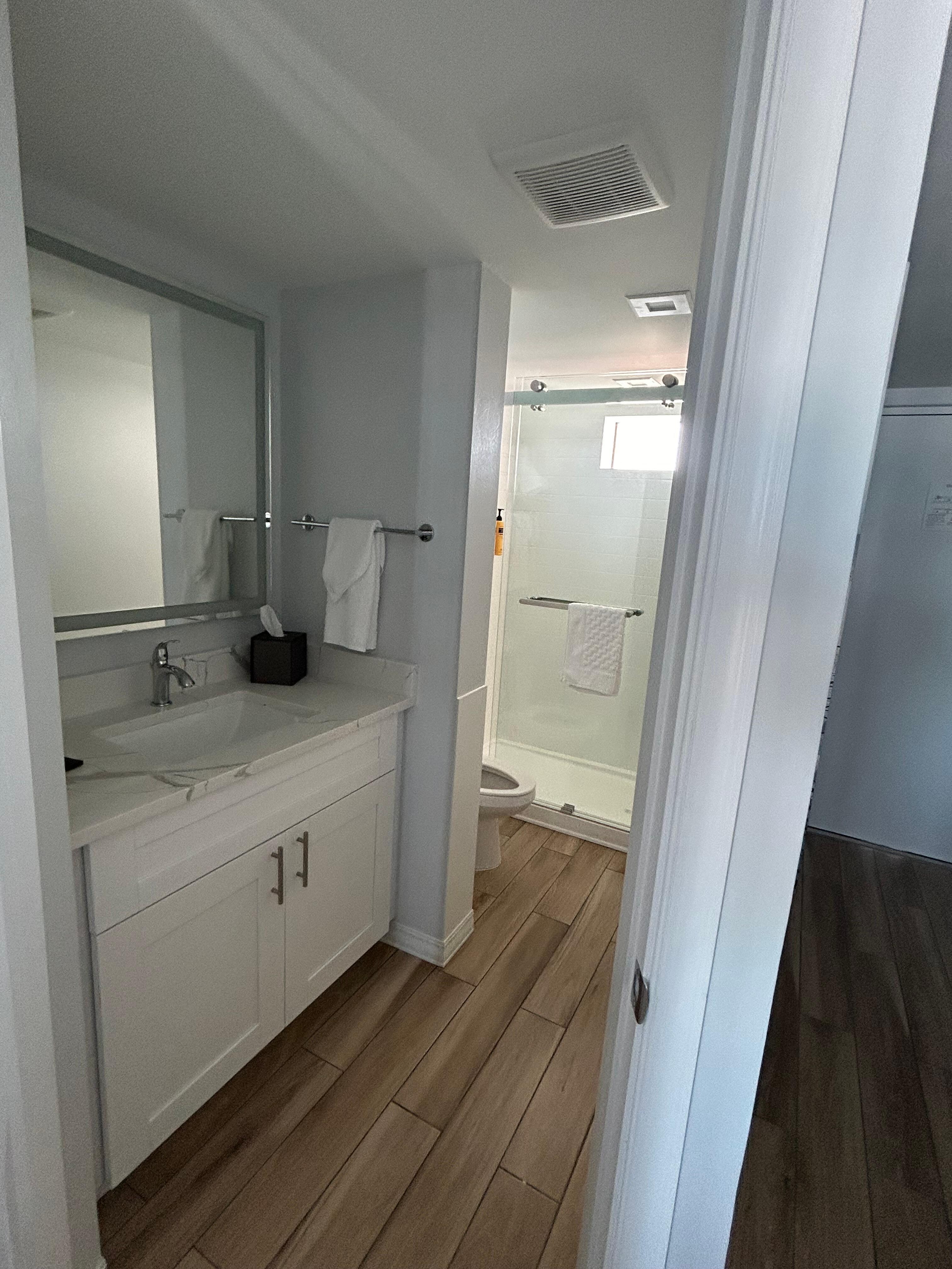 Bathroom standup shower, single vanity, toiletries included (shampoo, conditioner, body wash, hand soap, lotion).