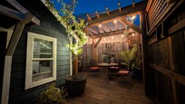 Outside sitting area of cottage at dusk with fairy lights.