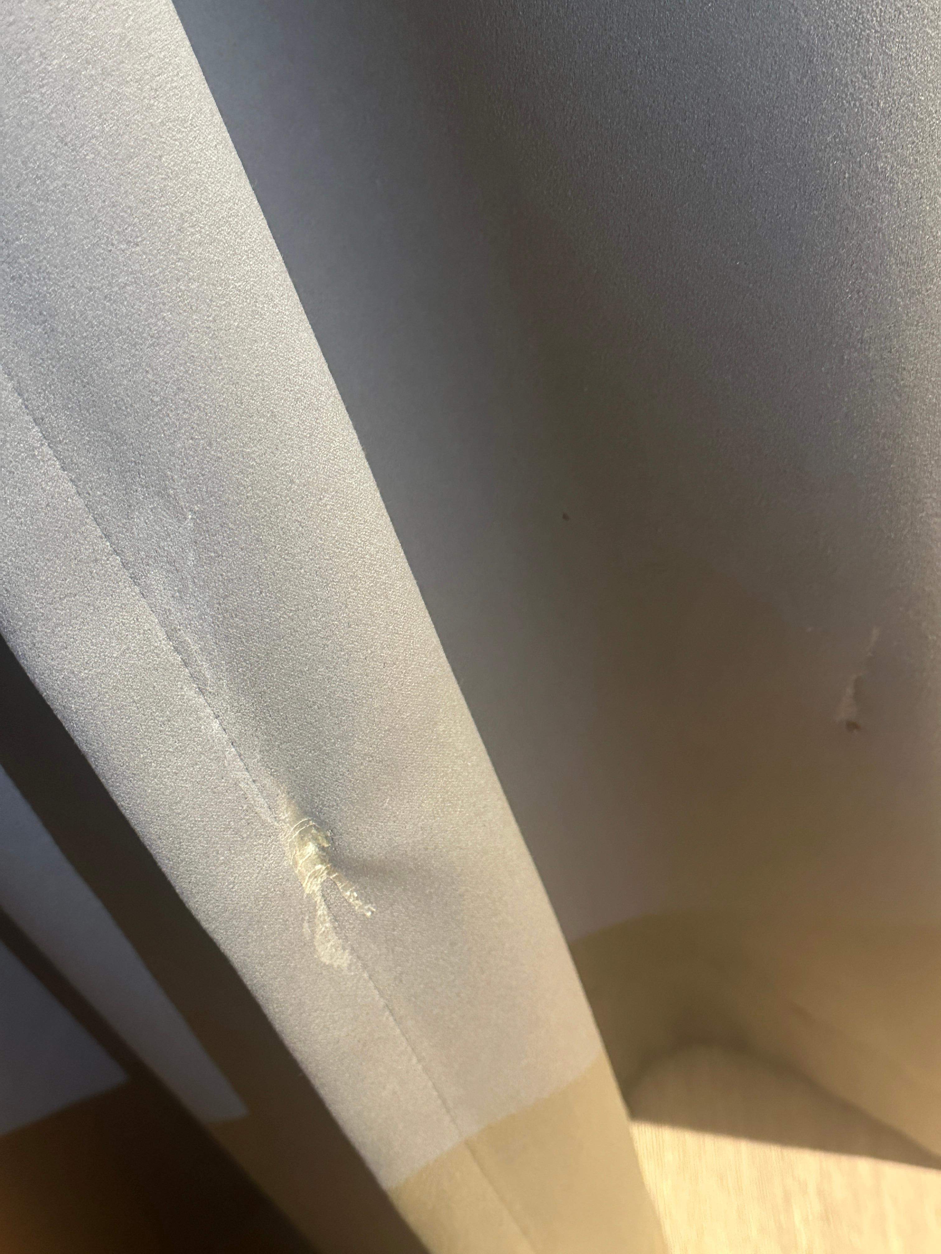 White stain on the curtains next to the bed 