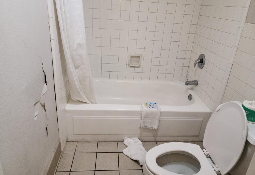 hole in wall and black mold in the corner by shower