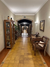O longo corredor é decorado com objetos antigos que contam histórias da vida na fazenda. Ferramentas rústicas, utensílios do cotidiano e peças cheias de memória adornam as paredes, criando um ambiente acolhedor e repleto de charme natural.