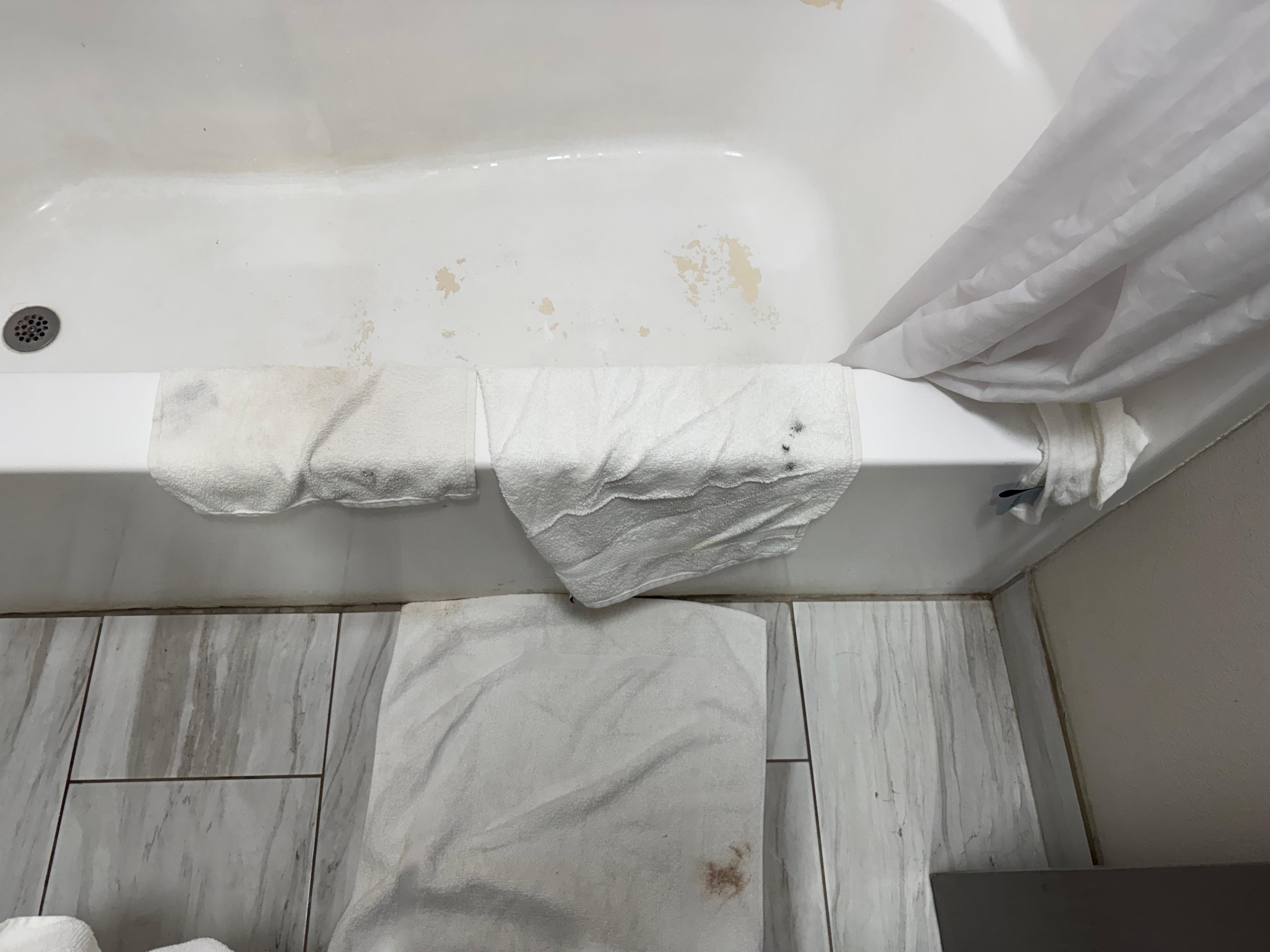 Linens had blood stains and black makeup or oil stains. Bathtub finish peeling. 