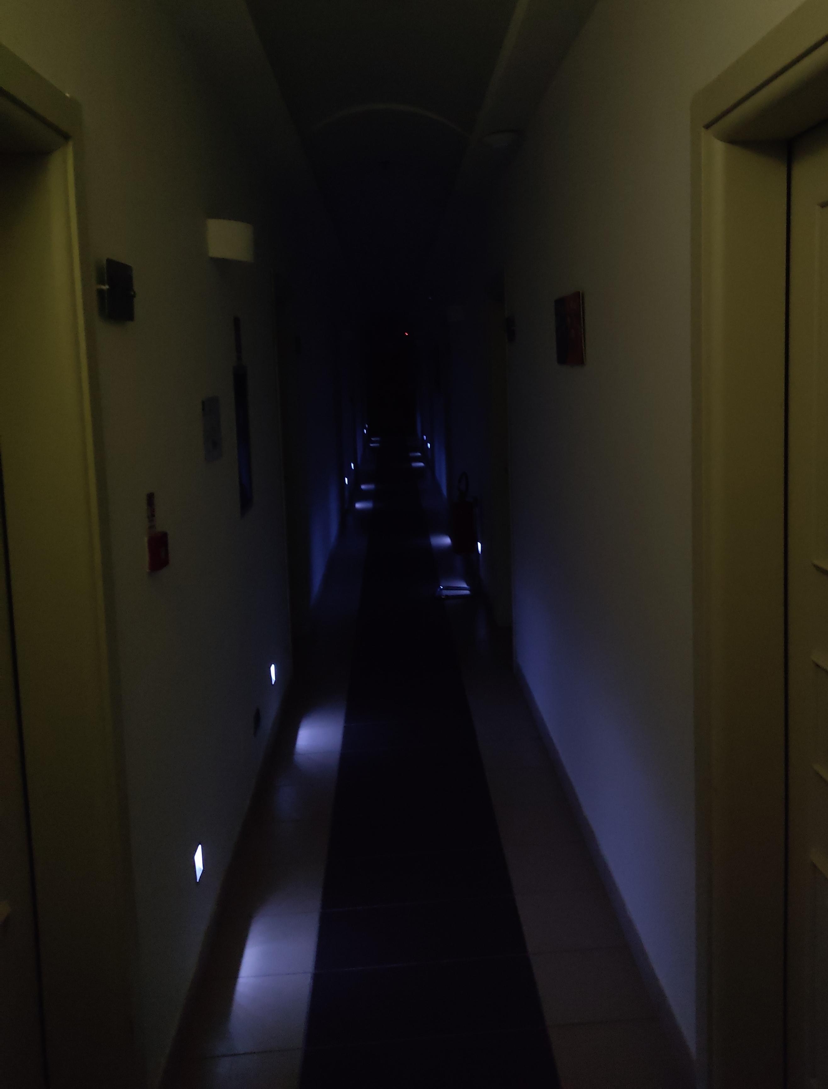 Corridor dark with only gentle lighting at low level. Main lights not used, making it impossible to see to put key in door. 