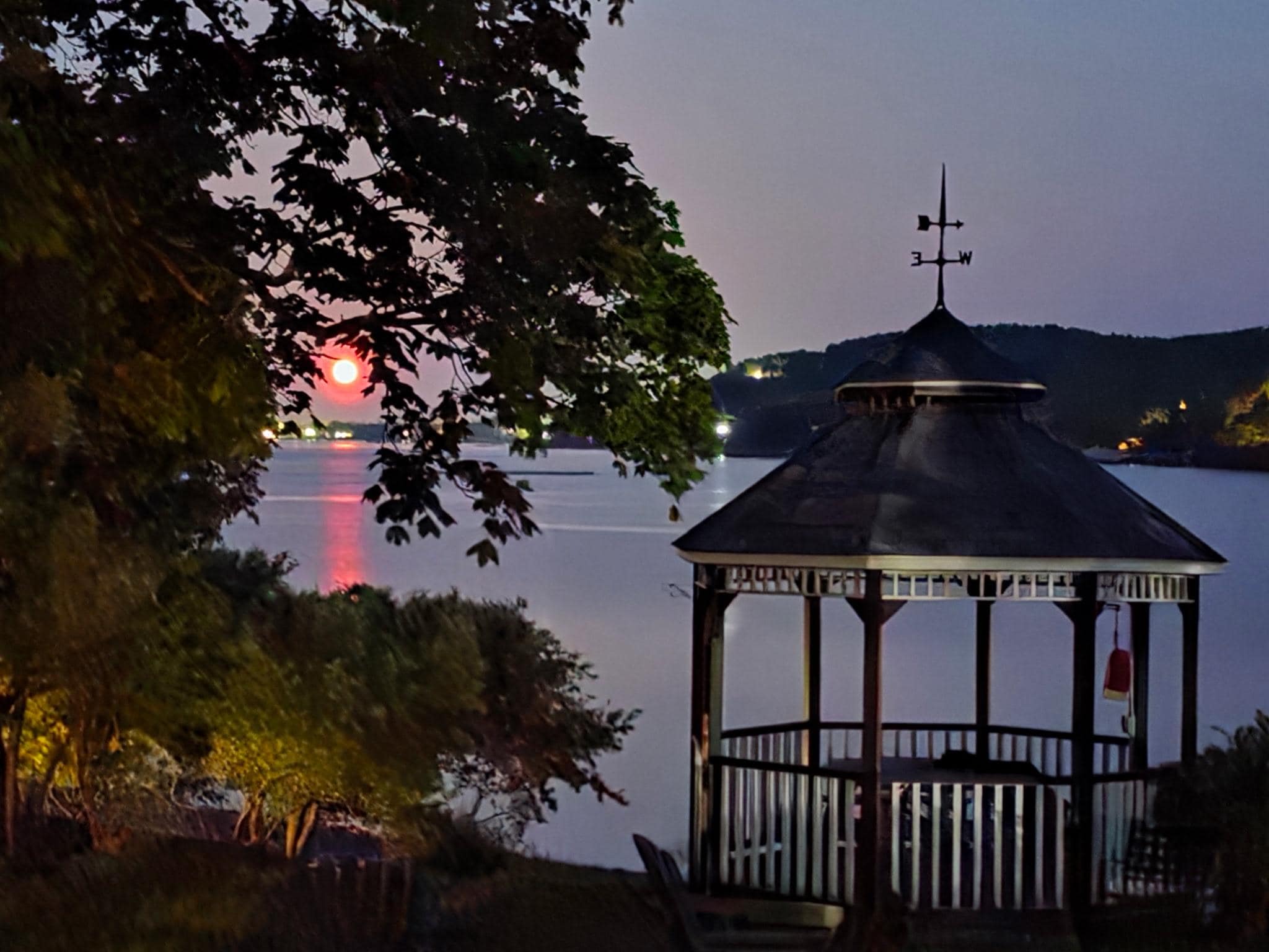 Strawberry moon coming up through property gazebo
