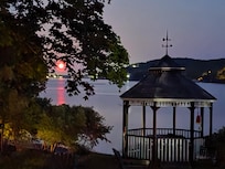 Strawberry moon coming up through property gazebo