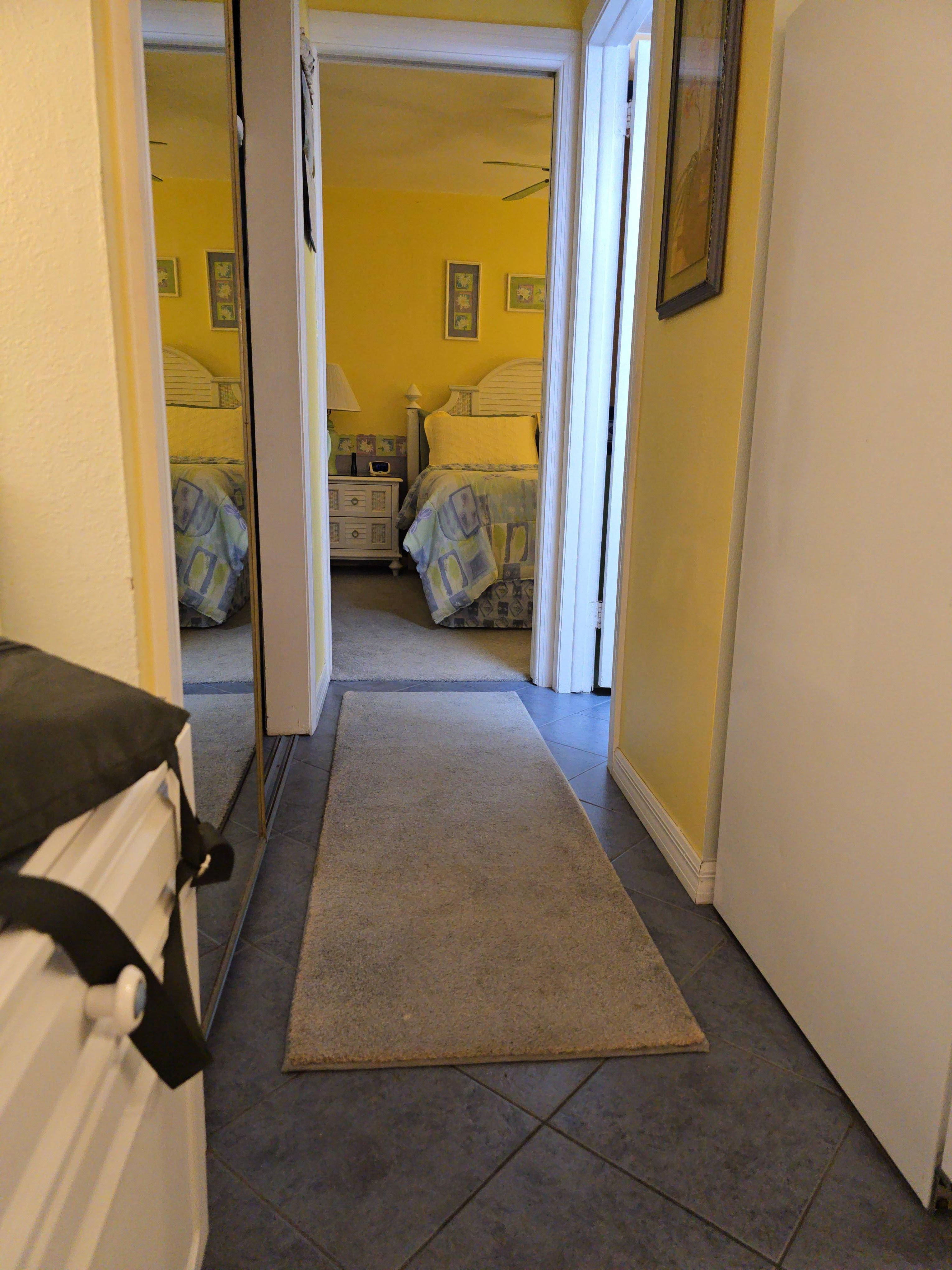 Large closet with mirrored doors on the left, bath on the right, bedroom at end of hall