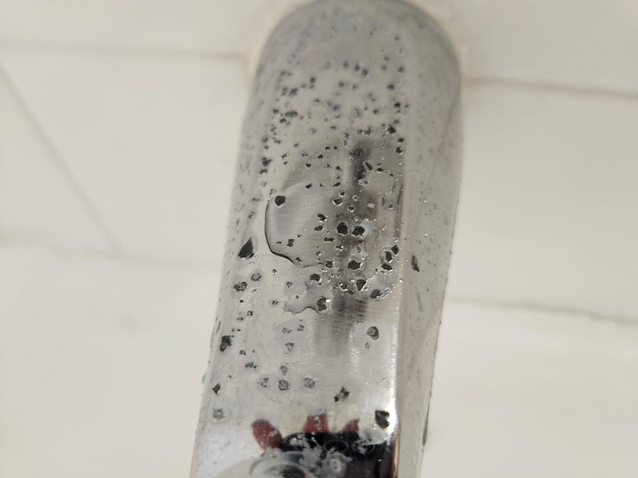 Green flecks of mold on the tub faucet 