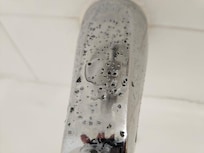 Green flecks of mold on the tub faucet