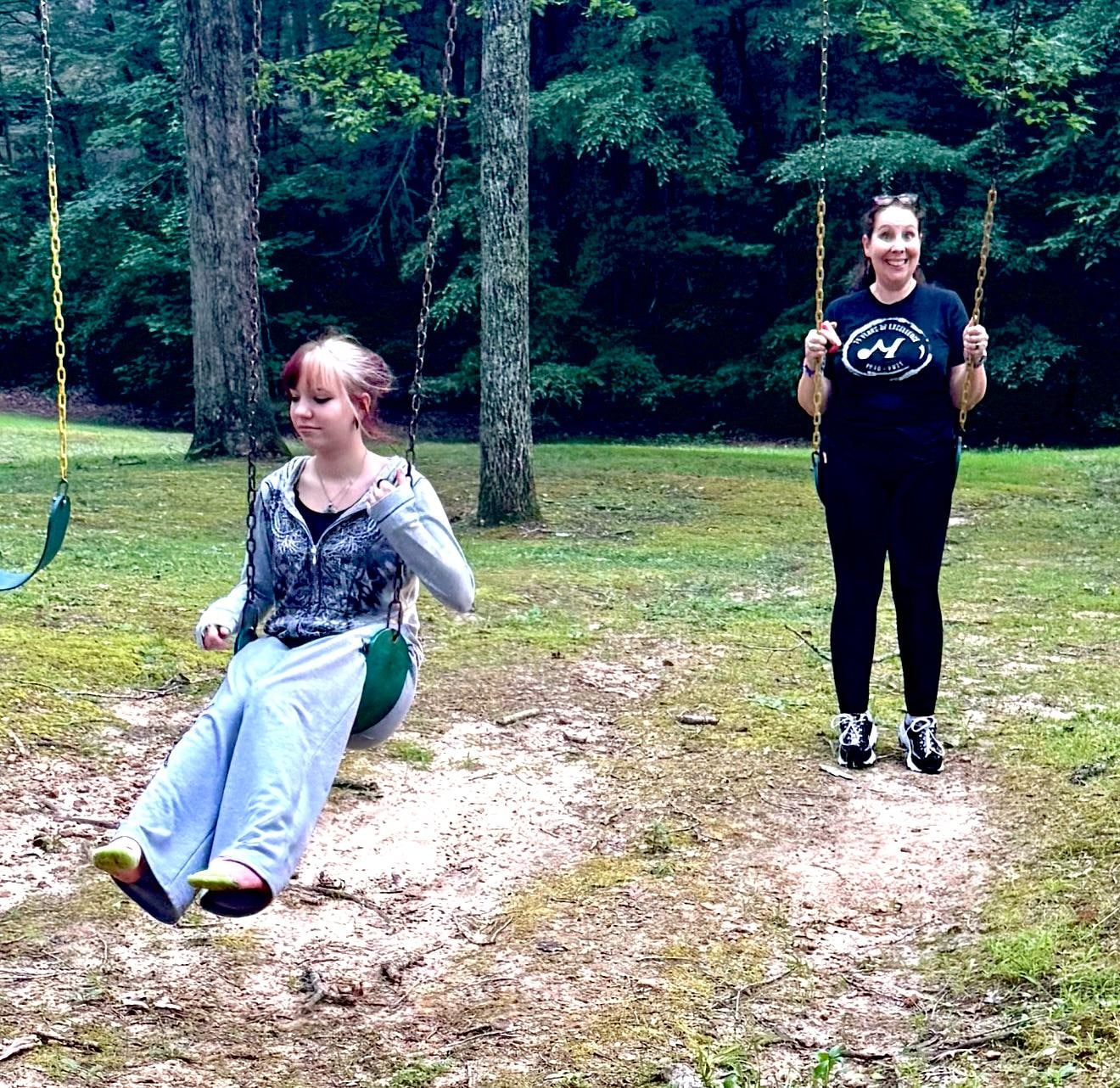 Mother & daughter on swing in backyard