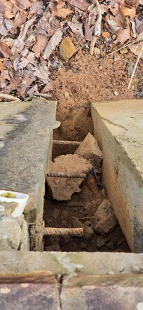 8" gap where the retaining wall has come apart and started sliding down the mountain.