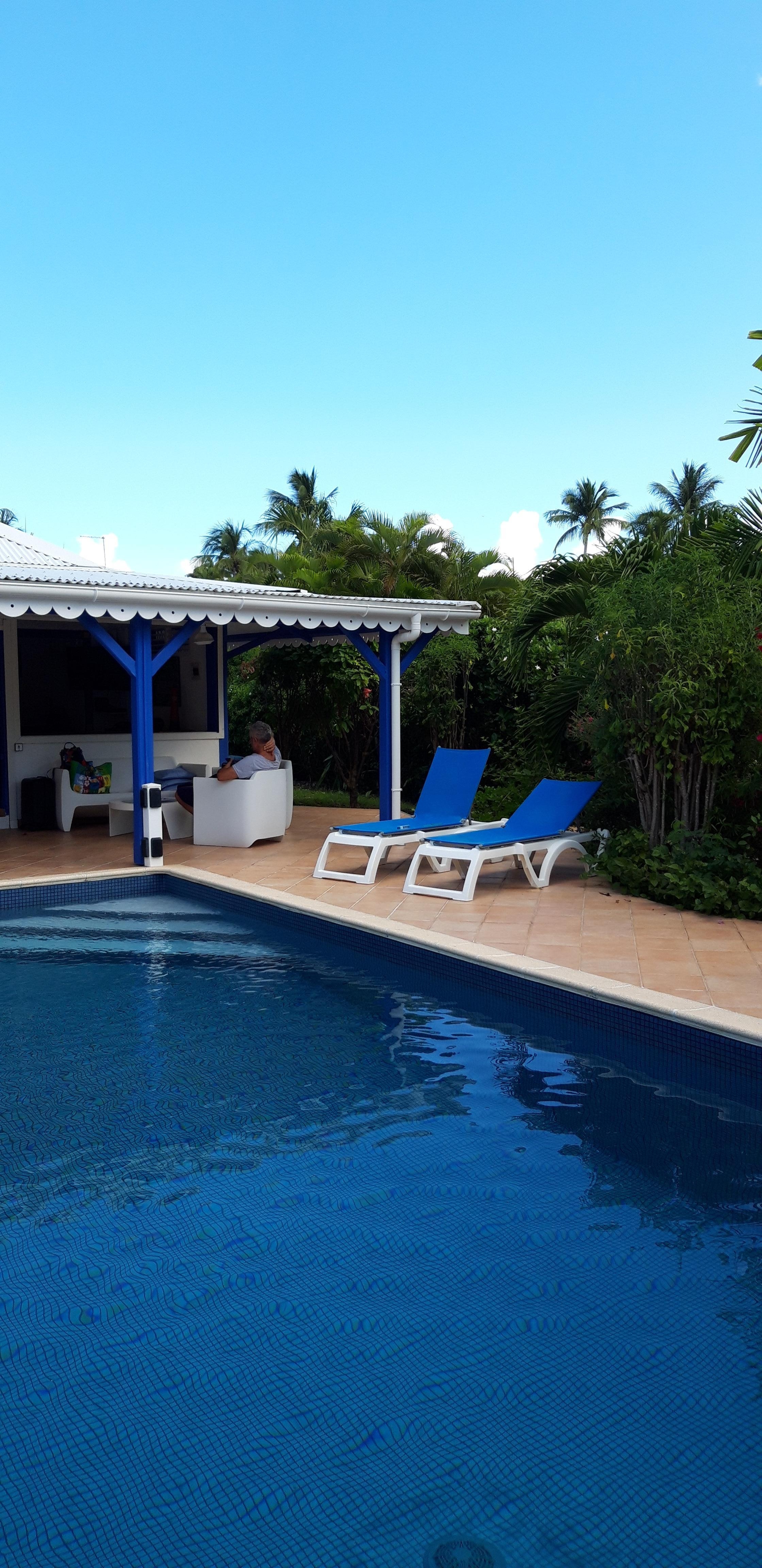 Vu sur le salon exterieur, d un cote de la piscine et deux bains de soleil, depuis la plage de la piscine