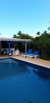 Vu sur le salon exterieur, d un cote de la piscine et deux bains de soleil, depuis la plage de la piscine