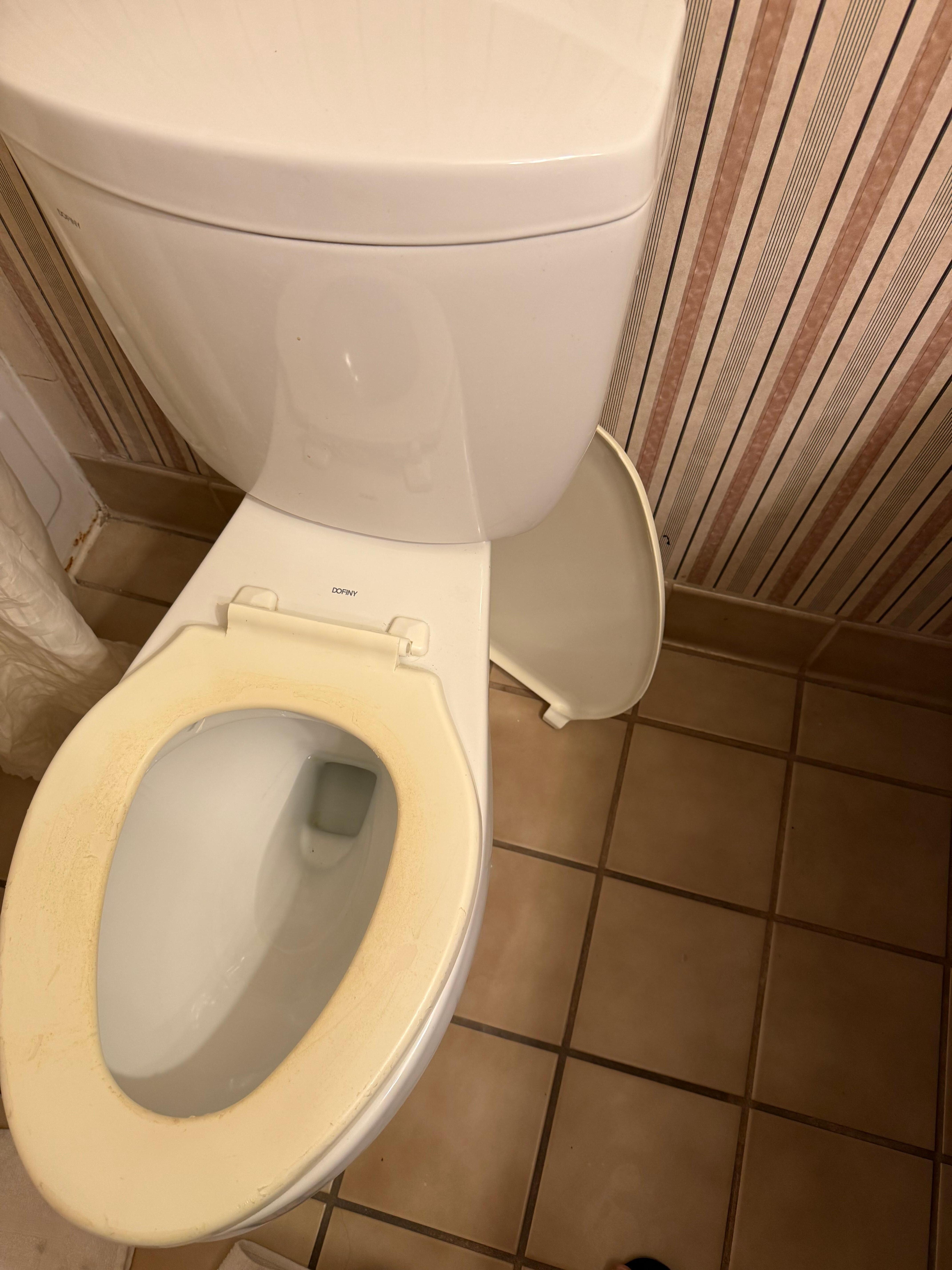Yellow stained toilet cover and seat top in the corner 