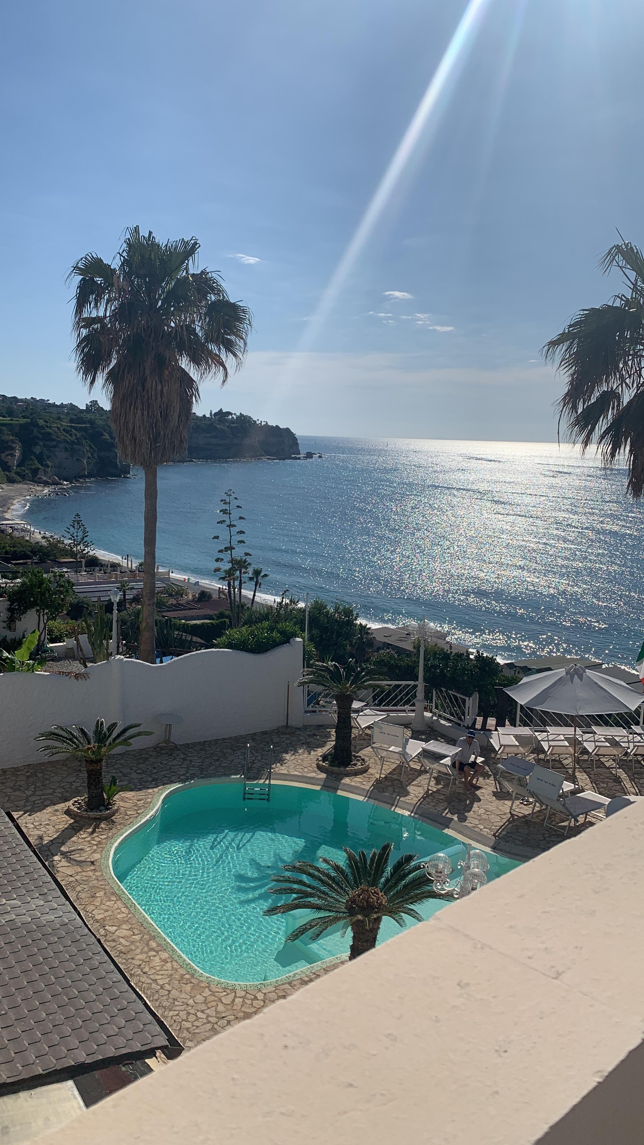 View from 2nd  patio of our bedroom with 2 chairs and small table.  View of pool and other side of ocean