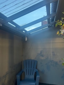 One of 2 spots to sit outside for the whole property is by the trash cans with a broken glass ceiling if it rains