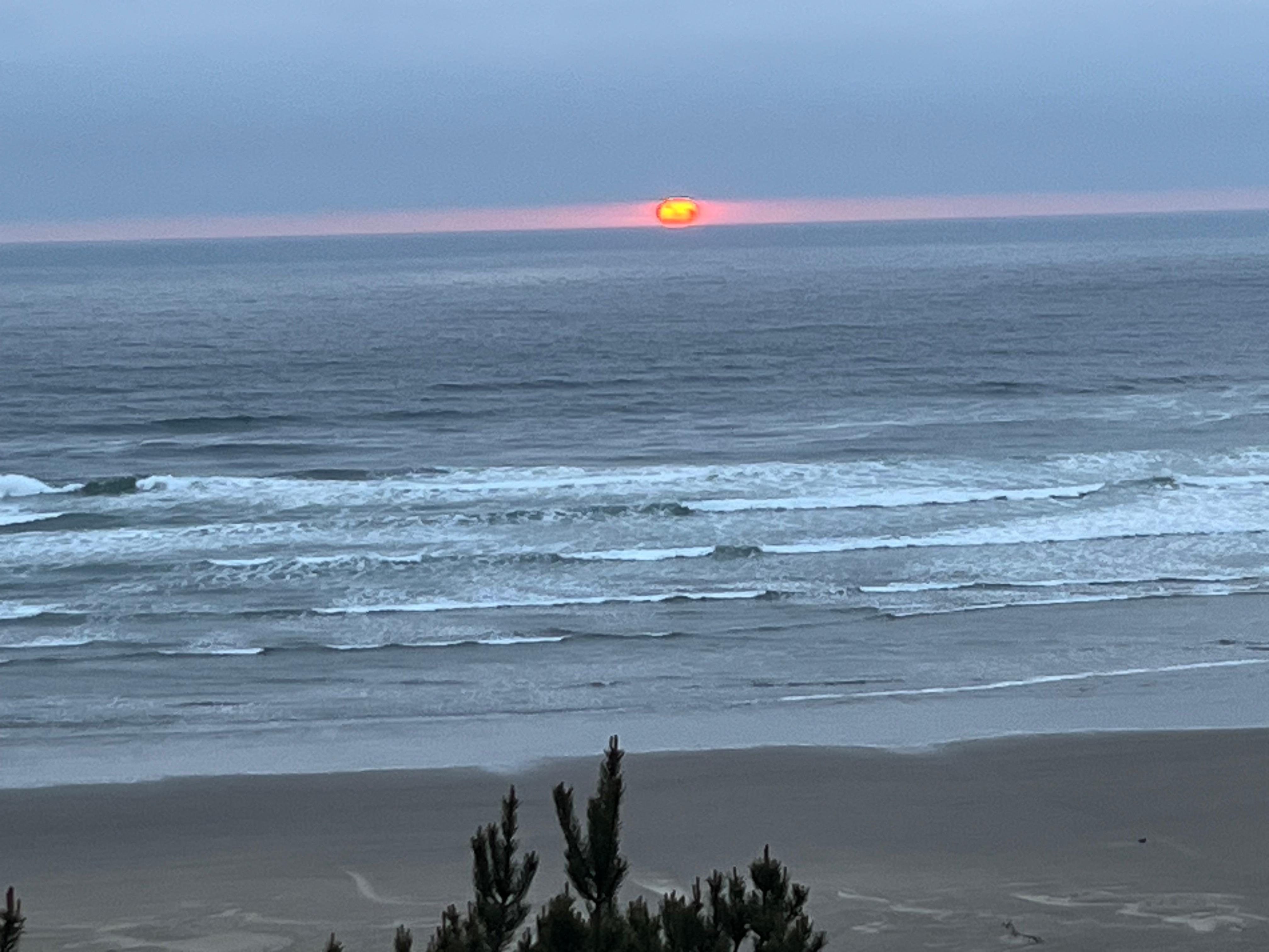 Sunset between bank of clouds and the ocean- from deck