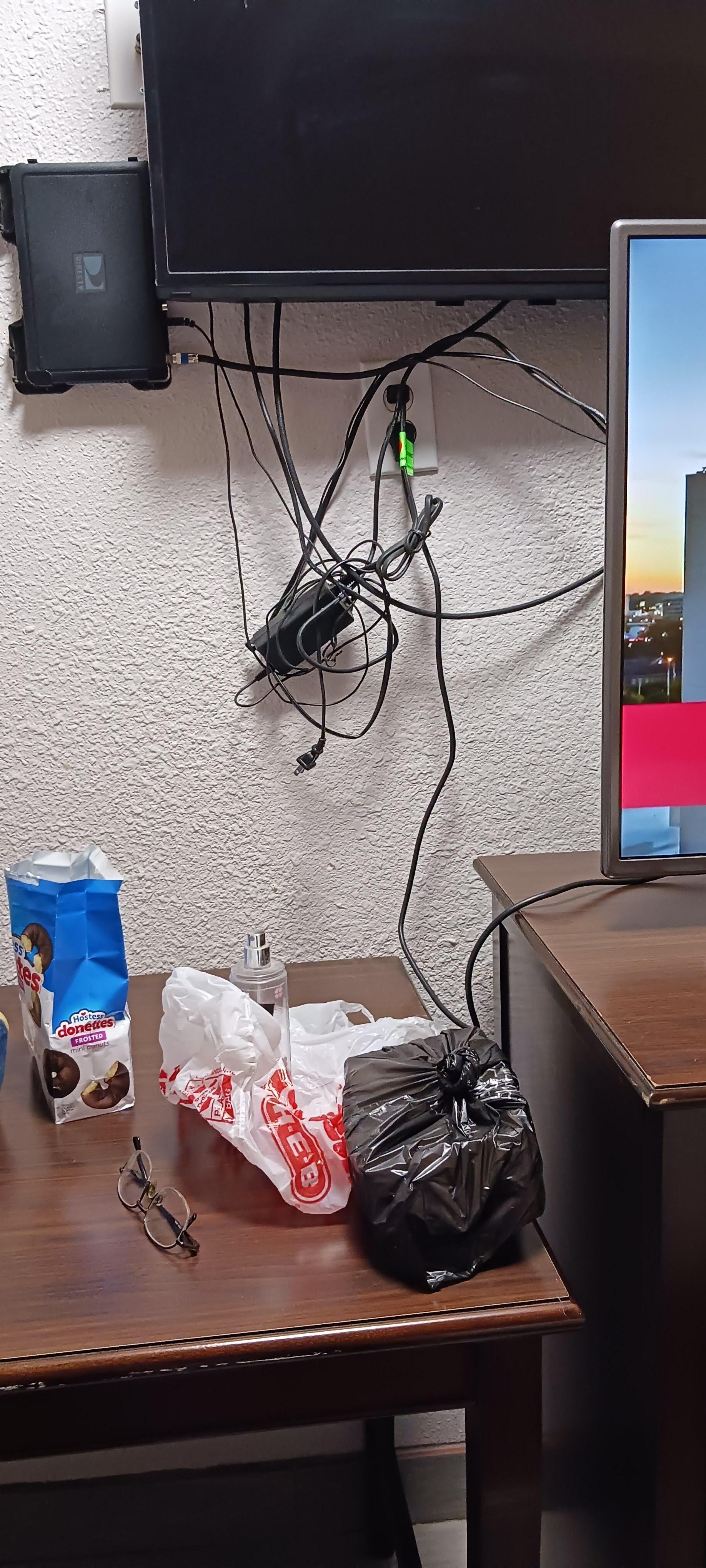 Electrical, cable TV power box and connections just hanging off wall next to TV 
