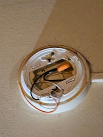 Smoke-carbon monoxide detector completely missing in living room. Note: wires are cut