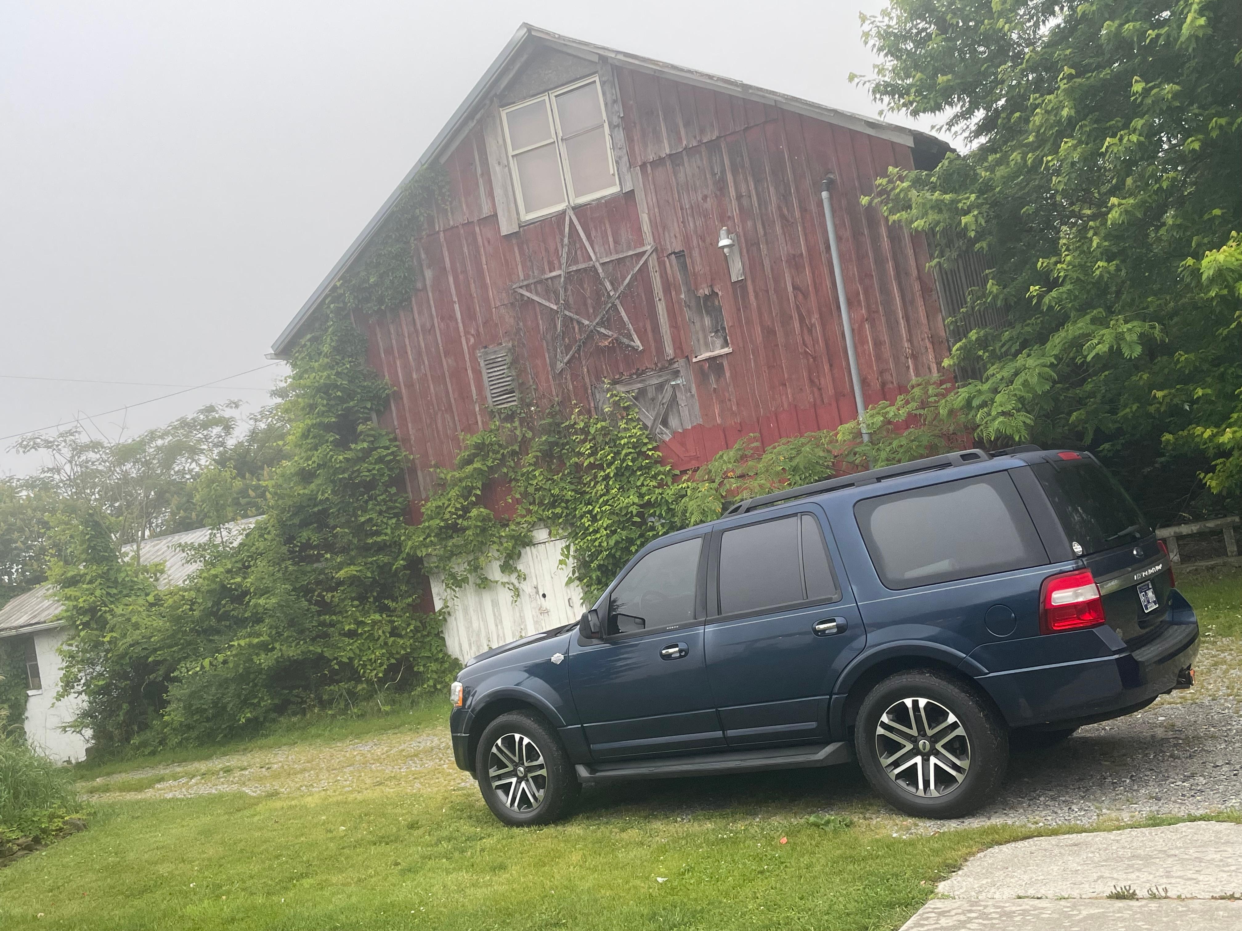 My ride with a barn in the background standing on the side porch. 