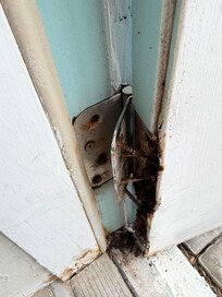 Rusted rotted door hinge.