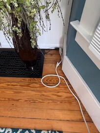 Black extension cord run though the floor vent connecting the A/C to a basement plug.