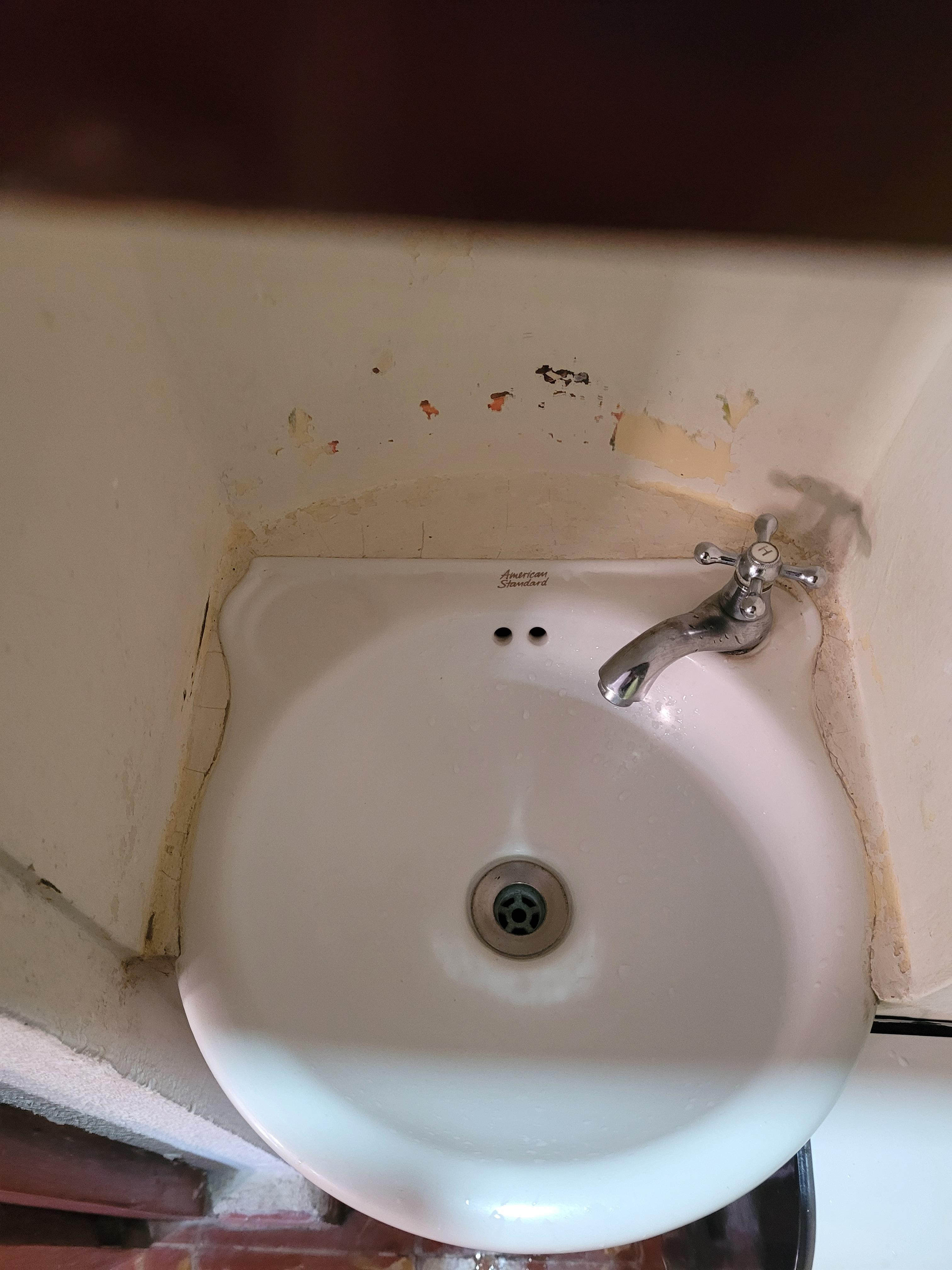 Unusable, dirty, run down sink in a whole in the wall, no soap