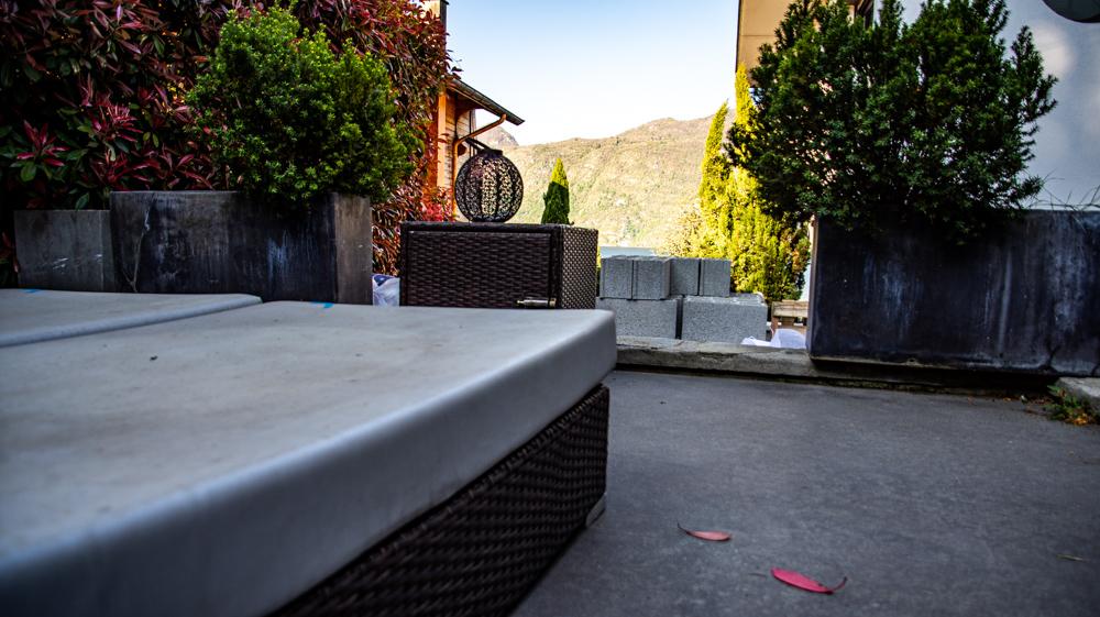 Terrasse de la chambre. Le sol et le mobilier sont sales. La petite vue est cachée par les parpaings. La route est juste derrière avec les voitures qui passent juste au dessus.