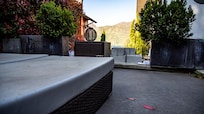 Terrasse de la chambre. Le sol et le mobilier sont sales. La petite vue est cachée par les parpaings. La route est juste derrière avec les voitures qui passent juste au dessus.