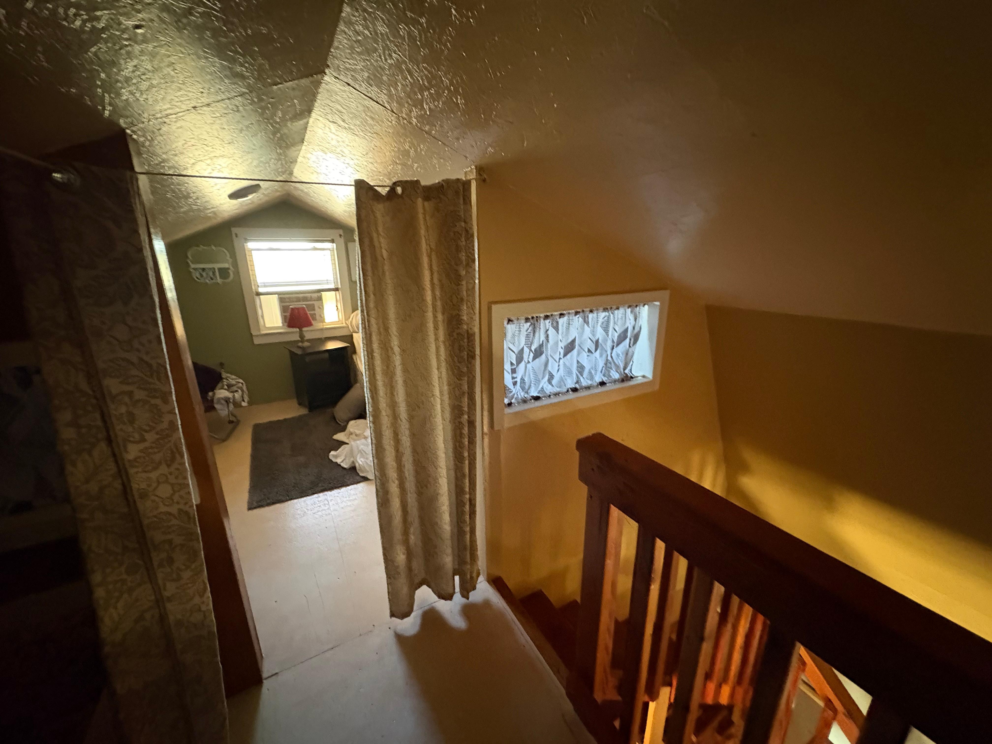 Upstairs bedroom with curtains instead of doors. 