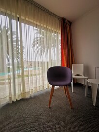 Muy bonito ventanal a la zona del jardín, piscina y mar. Las sillas y mesita blancas son para exterior.