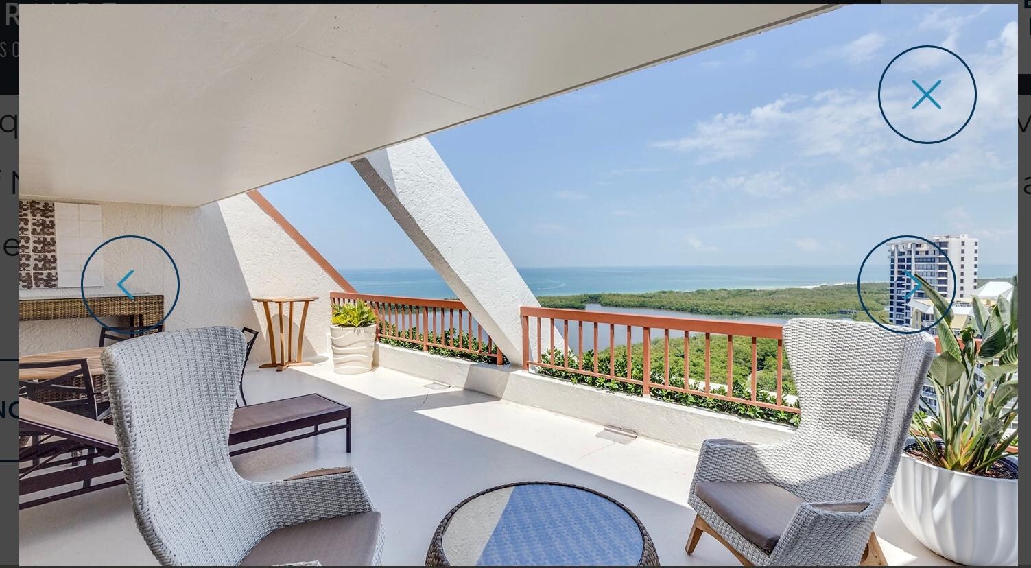 Online picture of balcony with nice plants and outdoor lounge chairs and table behind high back chairs. 