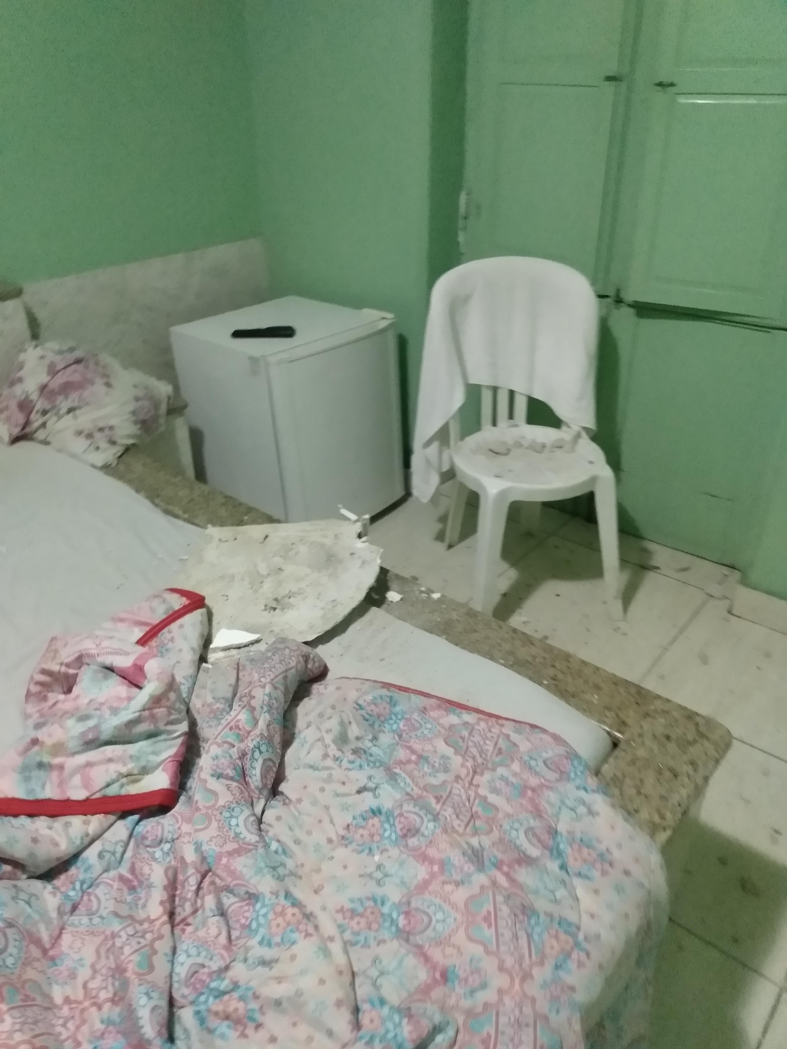 Sobre a cama, há o pedaço do gesso, do tamanho de um travesseiro, por sorte atingiu minha perna somente de raspão.