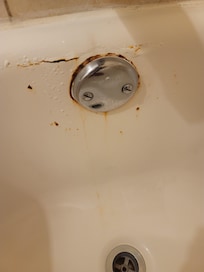 Cracked and broken upper drain cap in bathtub leading to leaks around tub and below.