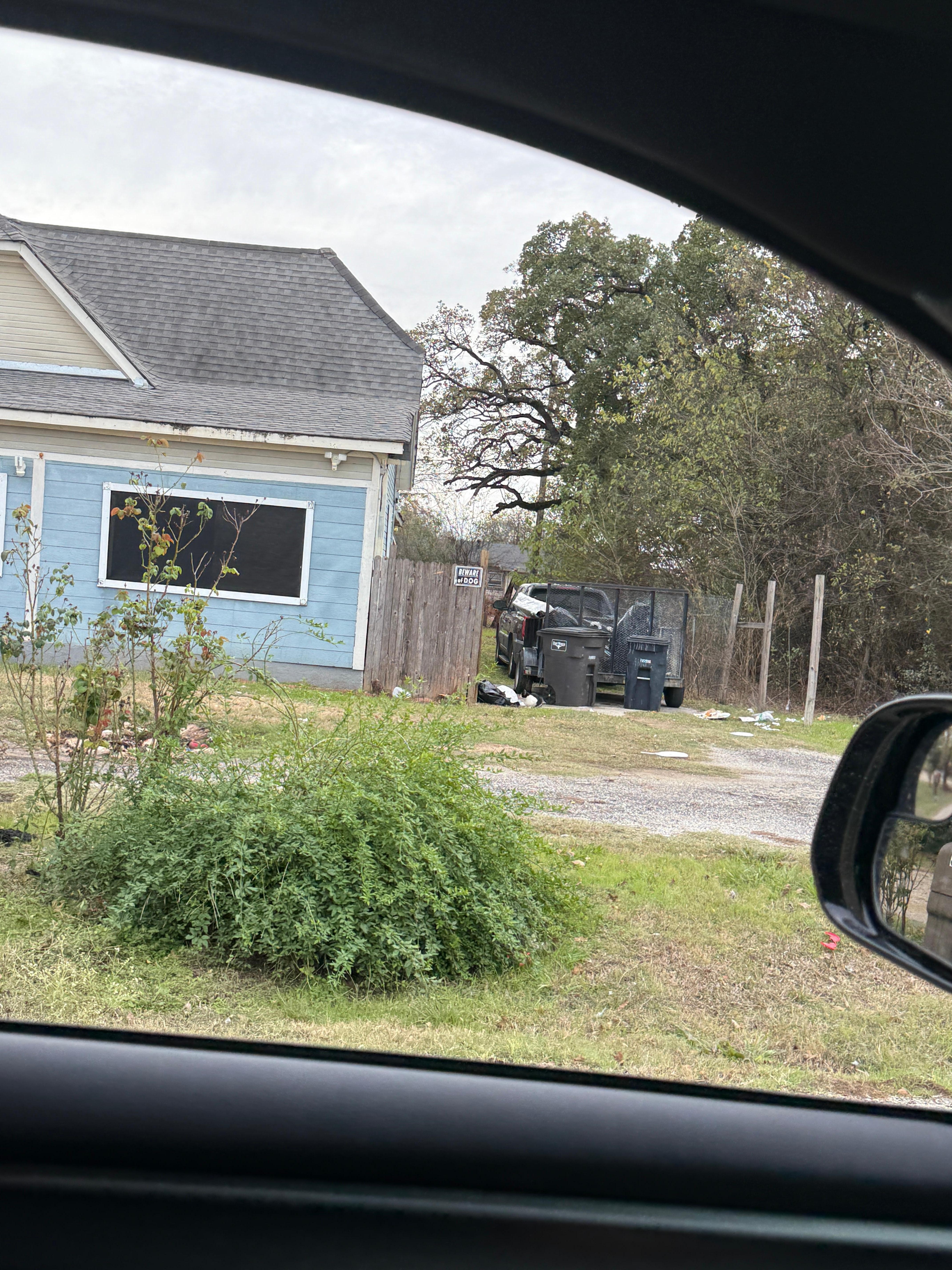 This is to the right of the home. There is a broken down car parked in the property full of rubbish along with rubbish on the grounds. Cats were also getting into the rubbish.