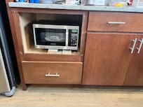 Microwave stuck in a broken cabinet
