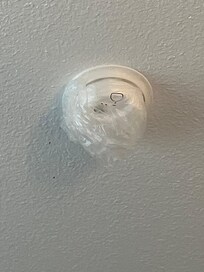Smoke detector on ceiling is covered with a plastic bag