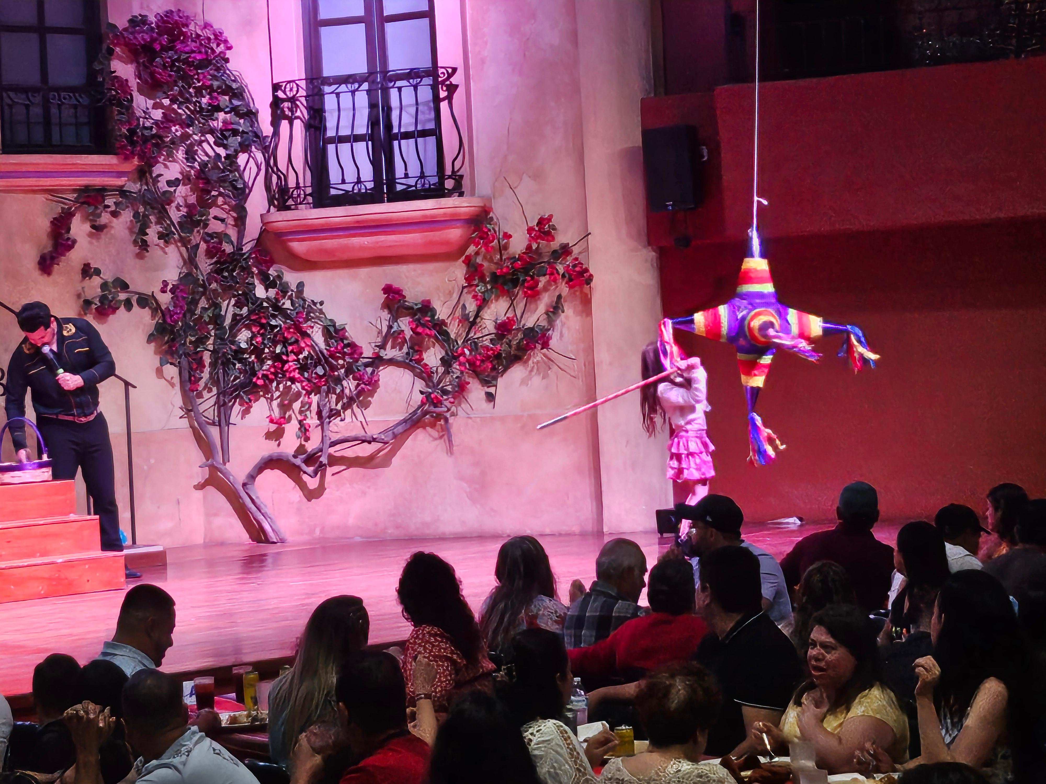 Children have fun with a piñata on stage during Mexican show