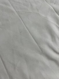 Sheets on bed covered with dog hair.